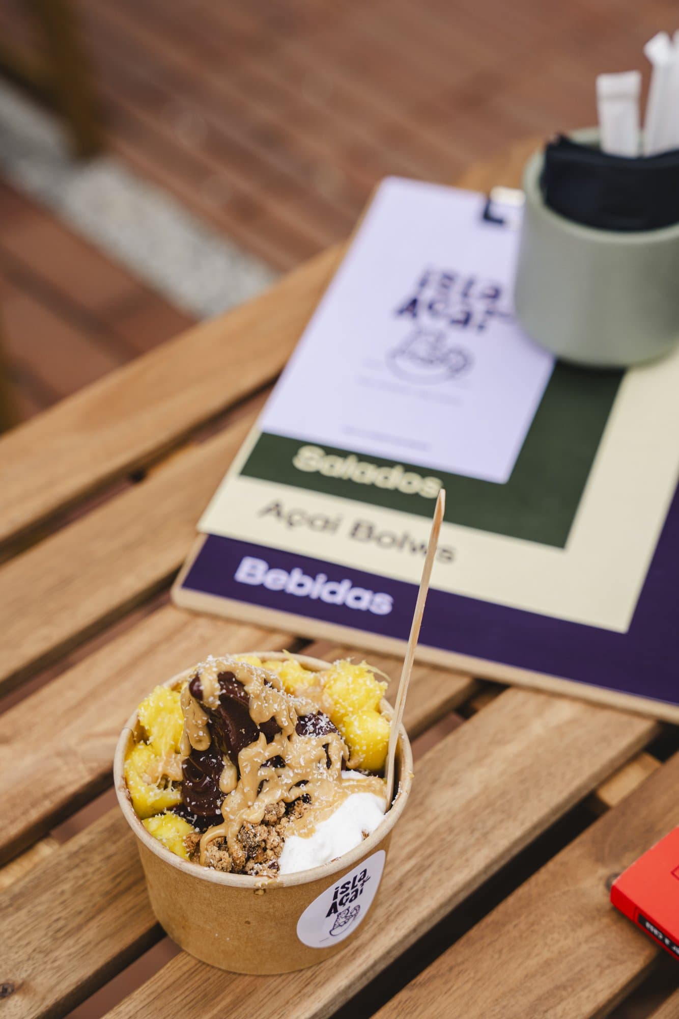 Açaí bowl de Isla Açaí sobre una mesa de madera junto a la carta